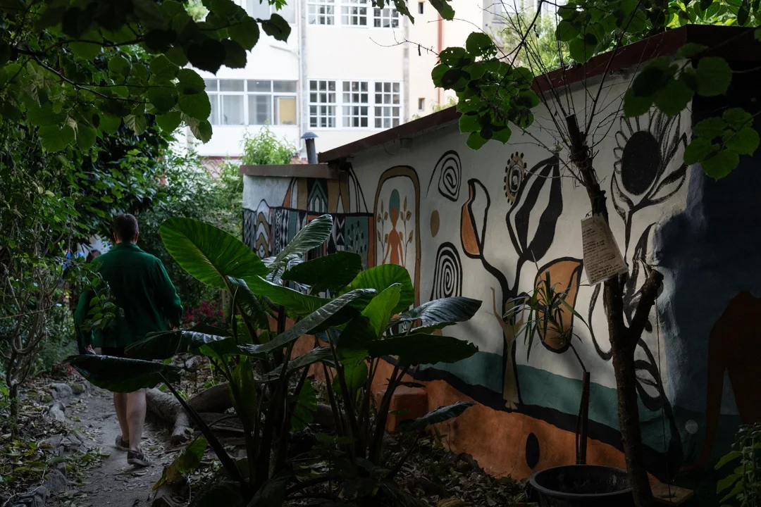 Mural painted on a garden wall at Espaço Compasso, among plants